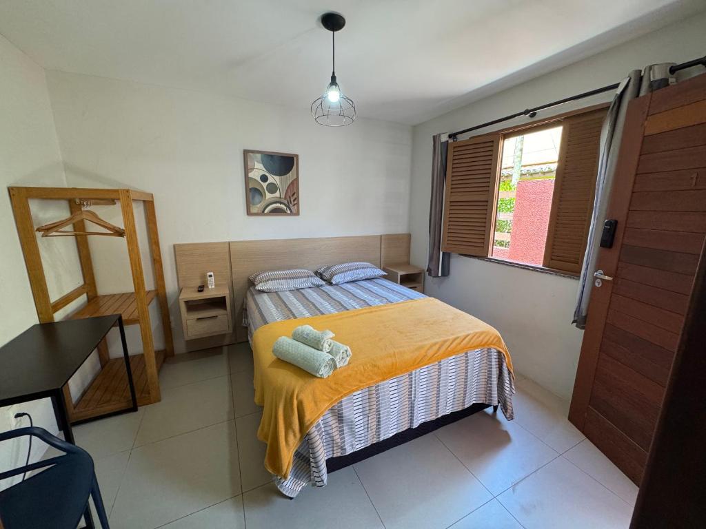 a bedroom with a bed with a yellow blanket at Suíte Peixe Espada in Praia do Forte