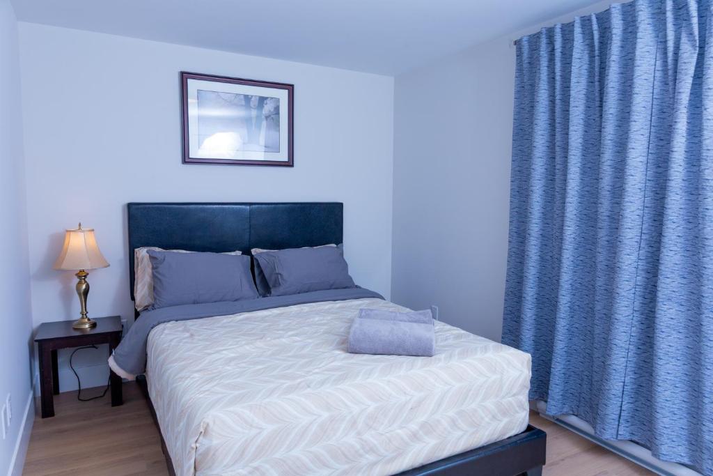a bedroom with a large bed with blue curtains at Honeycomb Suite in Riverview