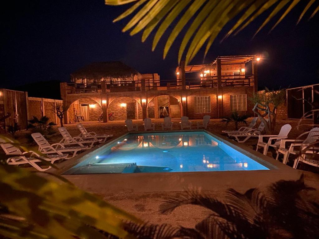 a swimming pool with chairs and a house at night at Baja69 Eco friendly Boutique stay in El Pescadero