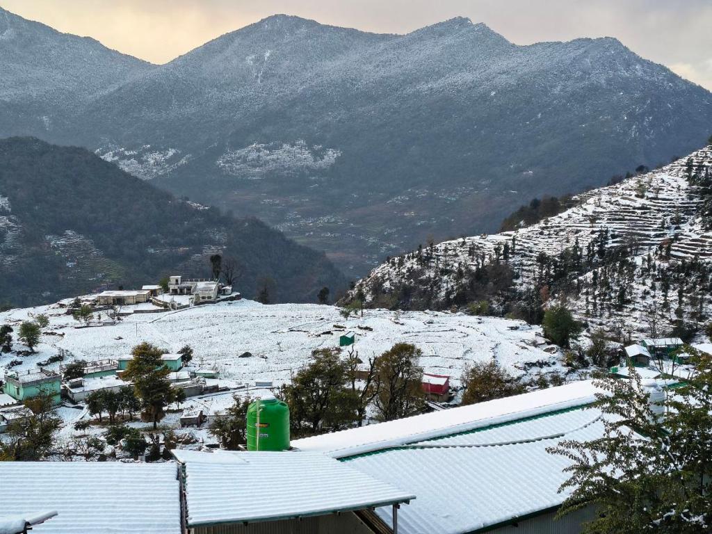 a snow covered valley with mountains in the background at ONLY CAFE Hotel in Chopta