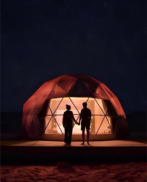 two people standing in front of a tent at night at The bubble camp in Wadi Rum