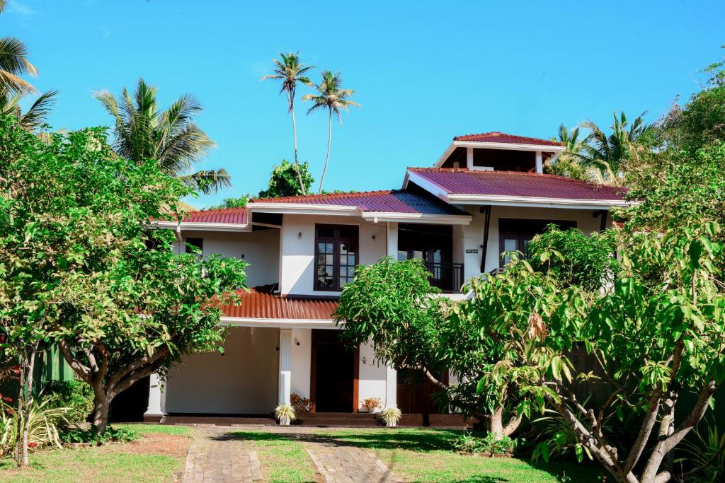 a house with palm trees in front of it at Villa Amora Hikkaduwa in Hikkaduwa