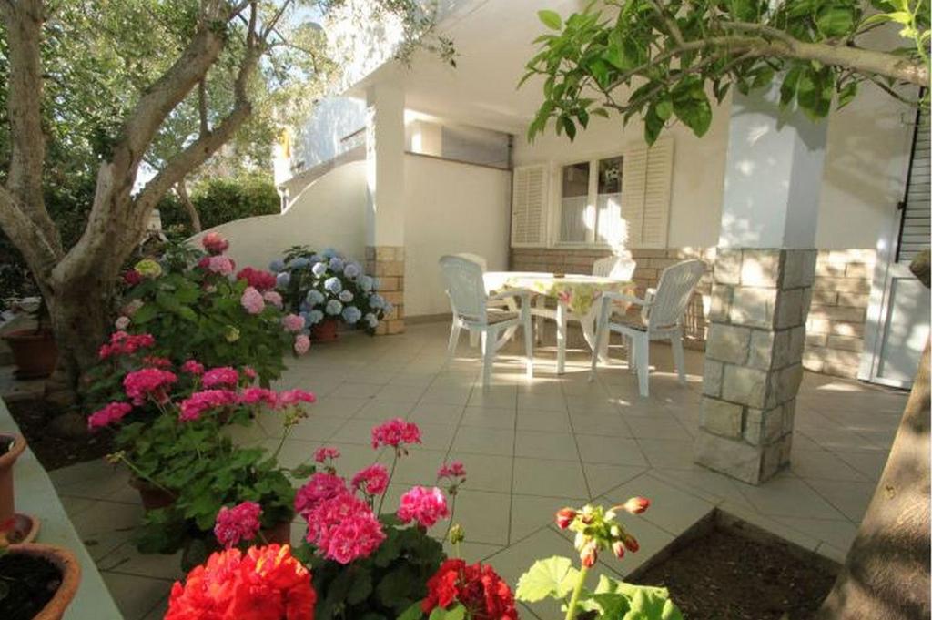 a patio with a table and chairs and flowers at Beautiful apartment with back yard and terrace - Apartments Vjenceslava XX in Novalja