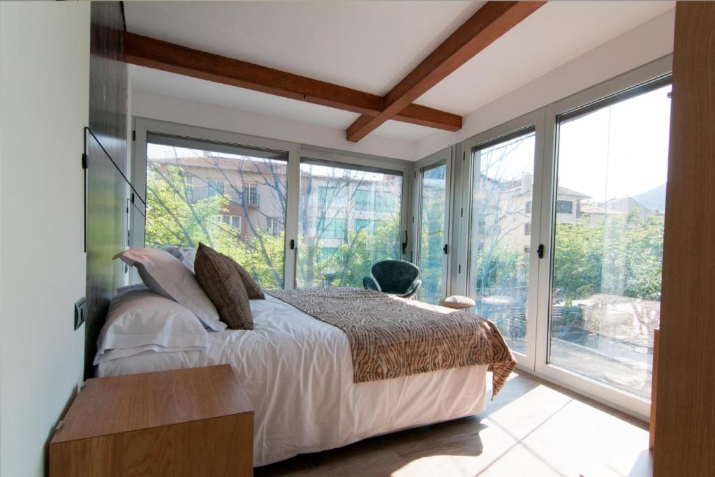 sypialnia z łóżkiem i dużymi oknami w obiekcie Cal Tonarro w mieście Organyà