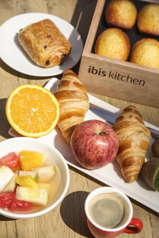 A sunlit breakfast assortment features croissants, pastries, fruit, and coffee.