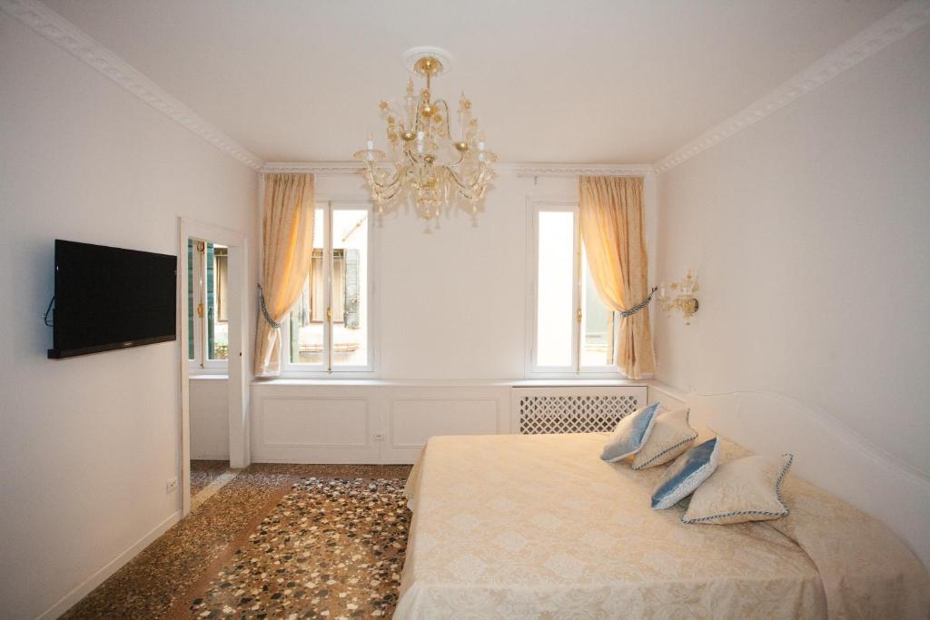 Habitación blanca con cama y lámpara de araña. en Antico Mercato, en Venecia