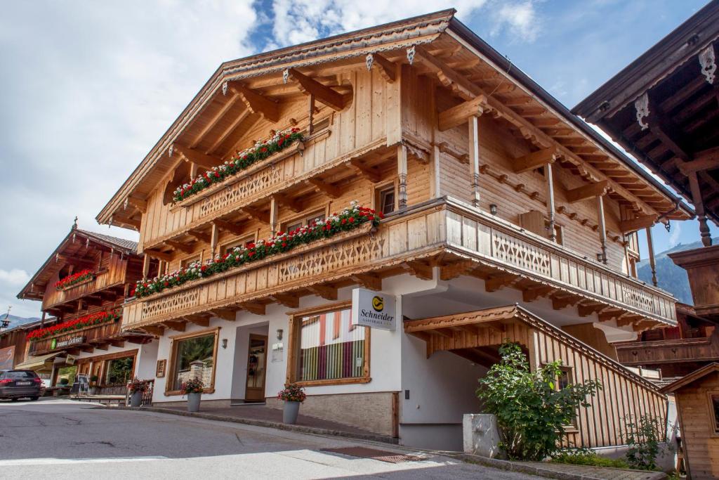 a wooden building with flower boxes on it at Das GÄSTEHAUS SCHNEIDER am Dorfplatz in Alpbach
