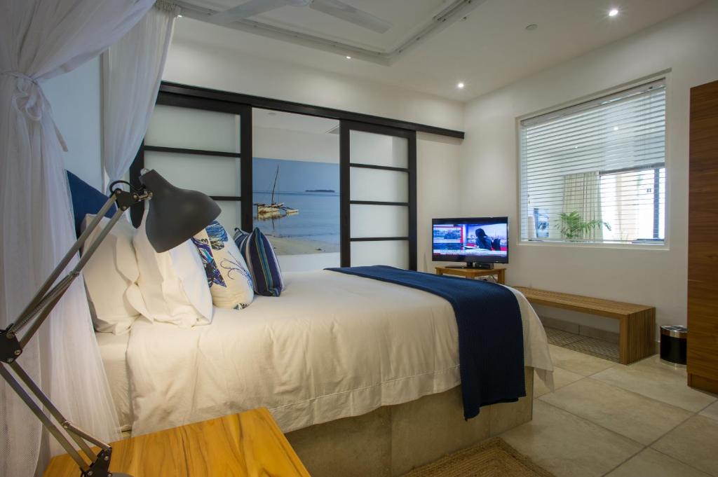 a bedroom with a bed with a television and a window at The Oyster Bay Hotel Suites in Dar es Salaam