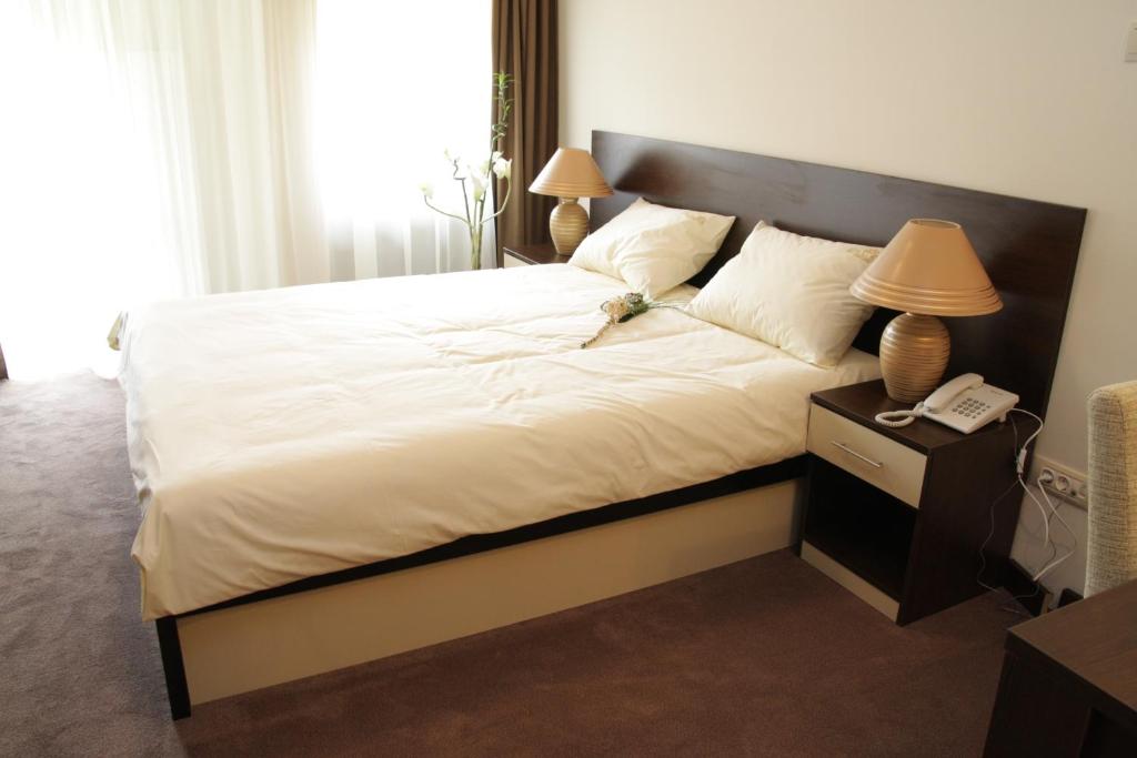 a bedroom with a large bed with a phone on a night stand at Hotel Royal Spa in Banja Koviljača