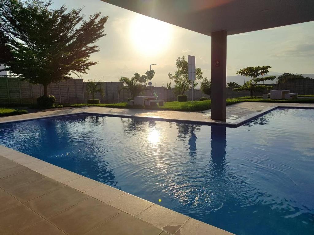 a large blue swimming pool with the sun in the background at La casa de Alex in San Juan Opico