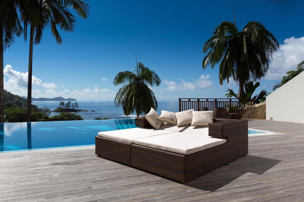 a wicker couch sitting on a deck next to a pool at Villas Palm Royal in Port Glaud