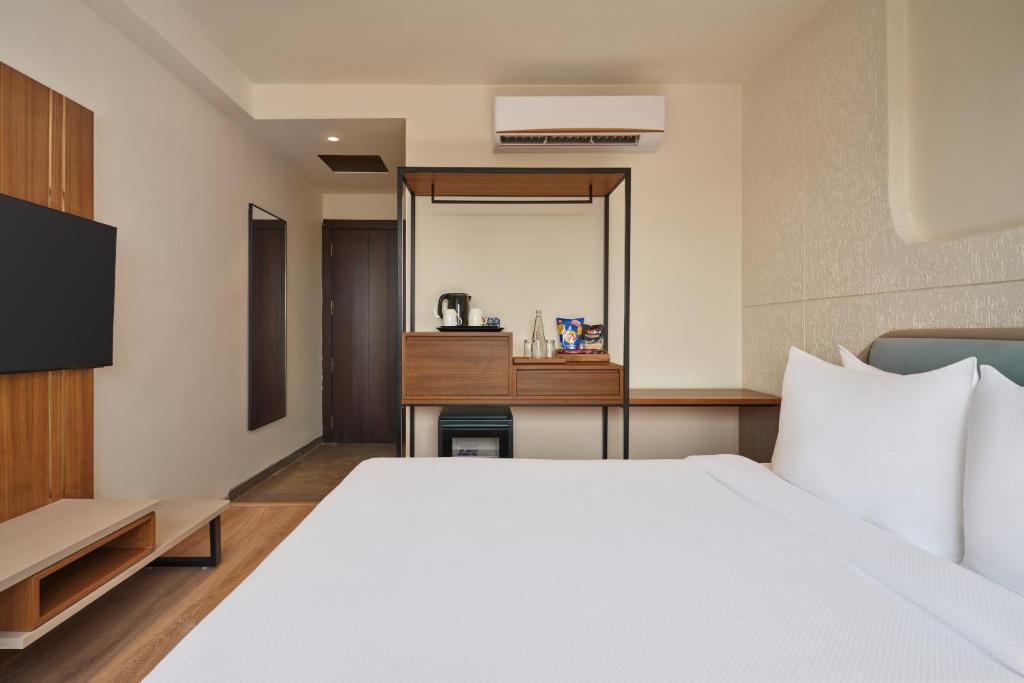 a bedroom with a large white bed and a mirror at Varay Grande in Ujjain