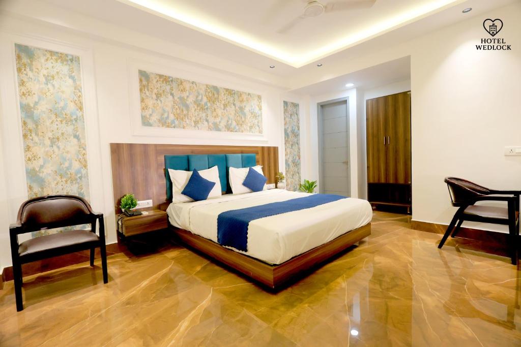 a bedroom with a king sized bed and a chair at Hotel Wedlock Grand Suites Gurgaon in Gurgaon