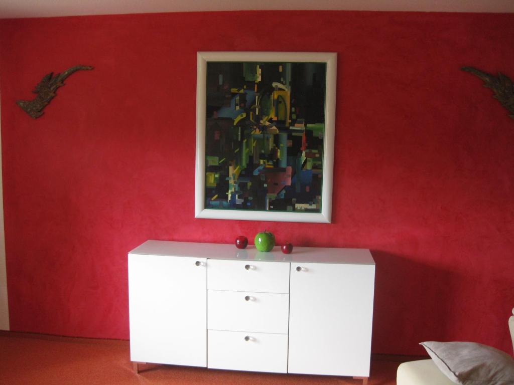 um armário branco num quarto vermelho com uma pintura em Ferienwohnung Marie em Feldberg