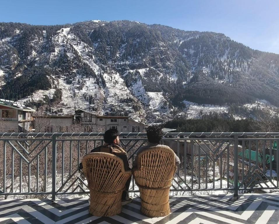 two people sitting on chairs looking at a mountain at Joeys Hostel Manali in Manāli