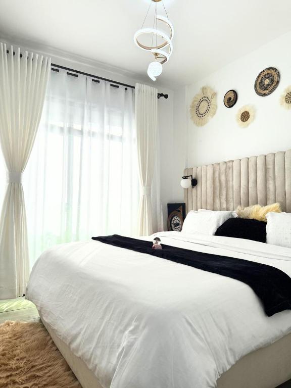 a bedroom with a large white bed and a window at Kitusuru staycation in Wabuga