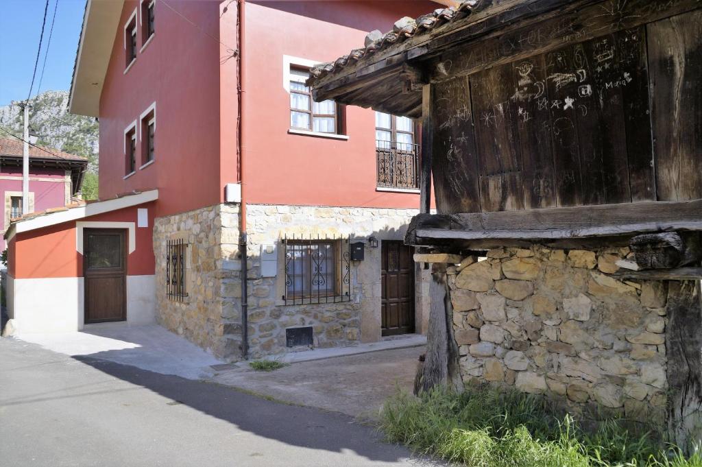 ein altes Steingebäude neben einem roten Gebäude in der Unterkunft Casa de Aldea El Sol in Poo de Cabrales