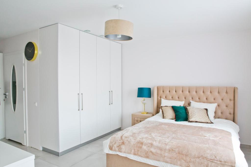 a white bedroom with a large bed with white cabinets at Elegant City Center Apartment 7A in Krakow