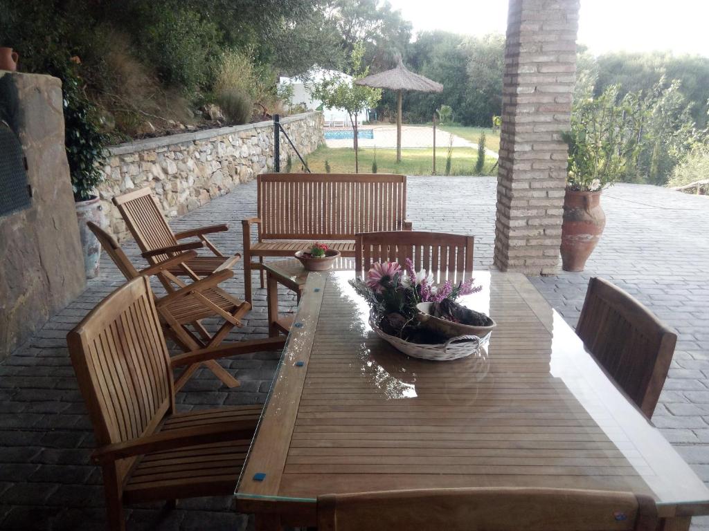 a wooden table with chairs and flowers on a patio at Mirador de Mulera in Ubrique