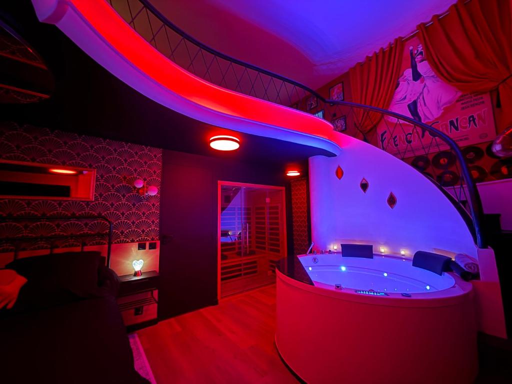 a bathroom with a tub in a room with purple lights at Le 1920- Spa & Sauna privé- Love Room in Le Havre