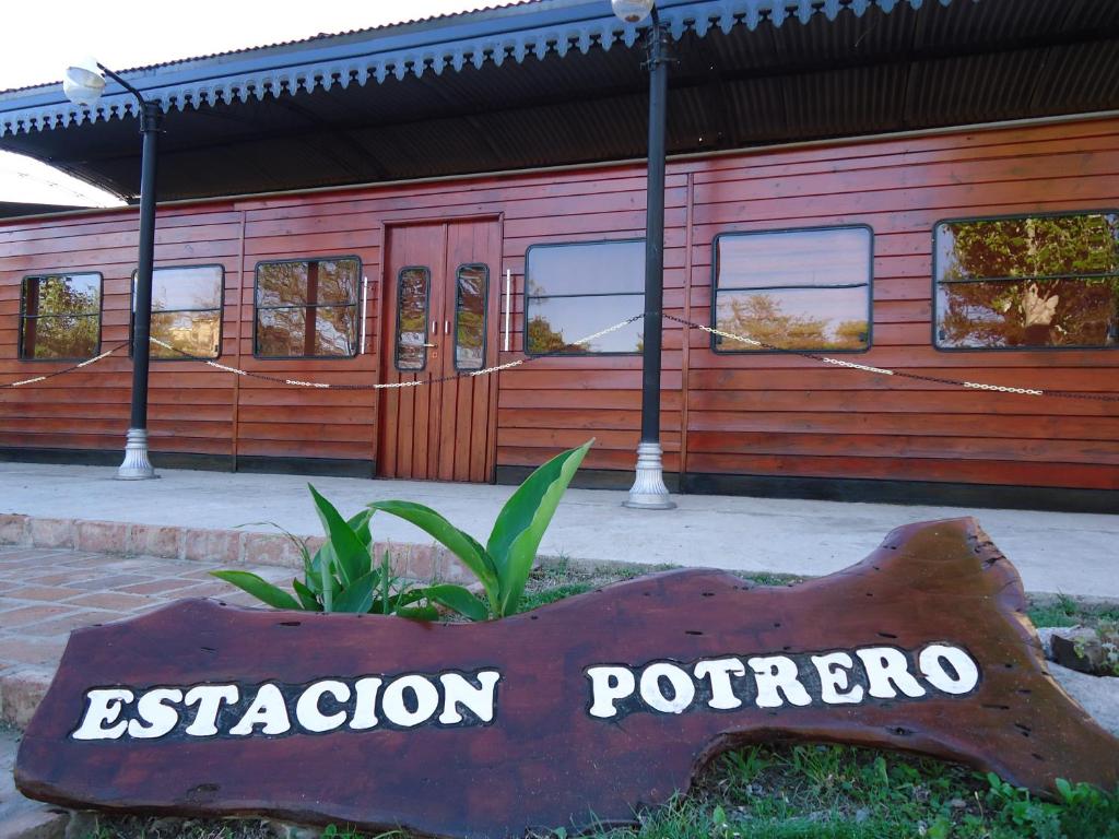 a sign in front of a red building at Estacion Potrero Cabañas y Habitaciones in Potrero de los Funes