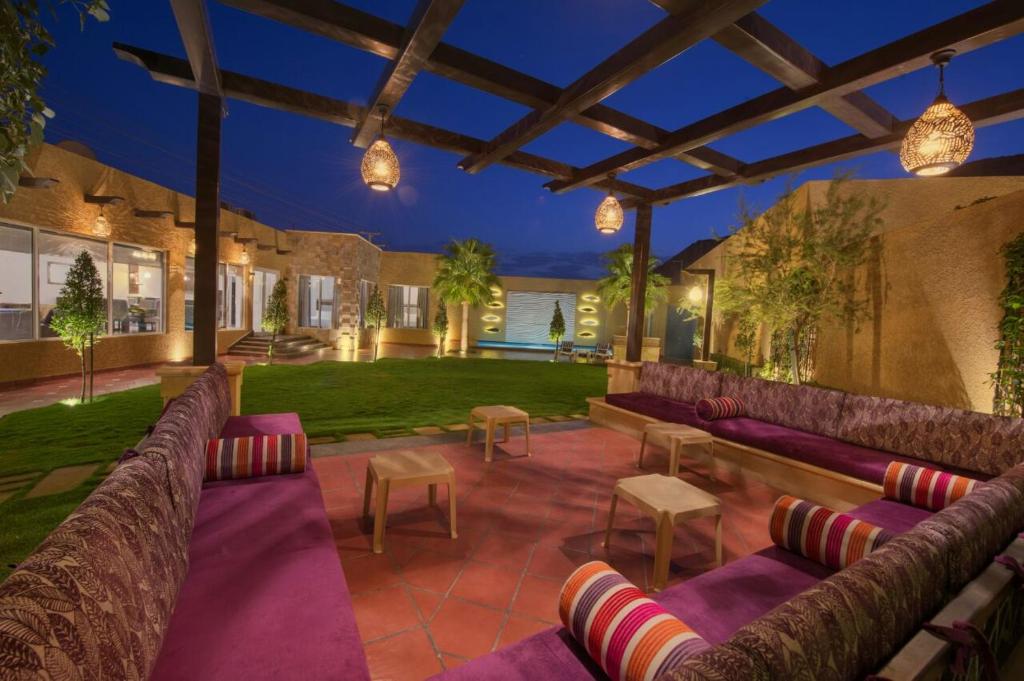 an outdoor patio with purple couches and a yard at Marbella Resort in Al ‘Ammārīyah