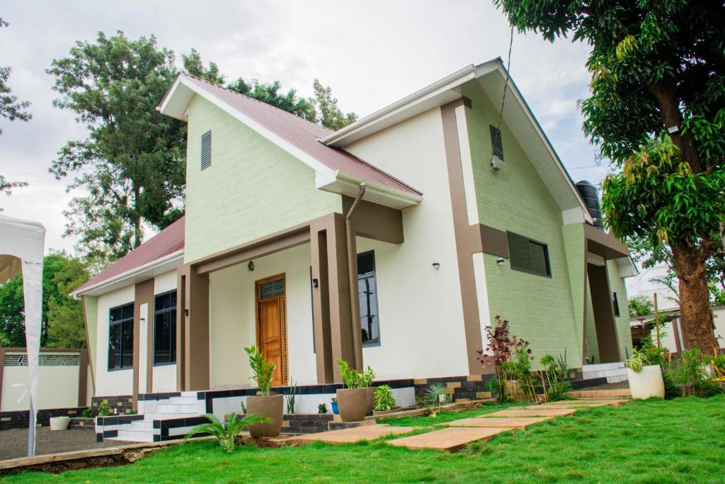 a green and white house with a yard at KiliView Homestay in Moshi