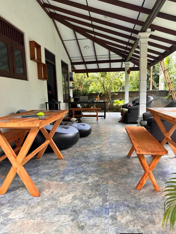 a patio with wooden picnic tables and couches at R BackPacker Hostel in Ahangama