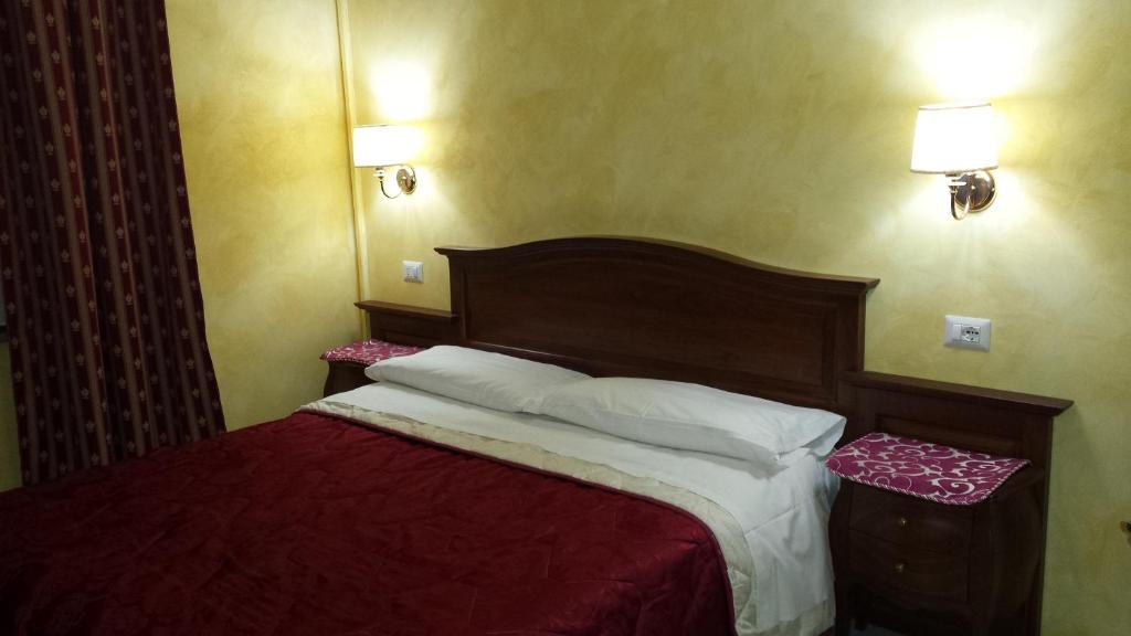 a bedroom with a bed with red sheets and white pillows at 3 Lati di Pitagora B&B in Rome