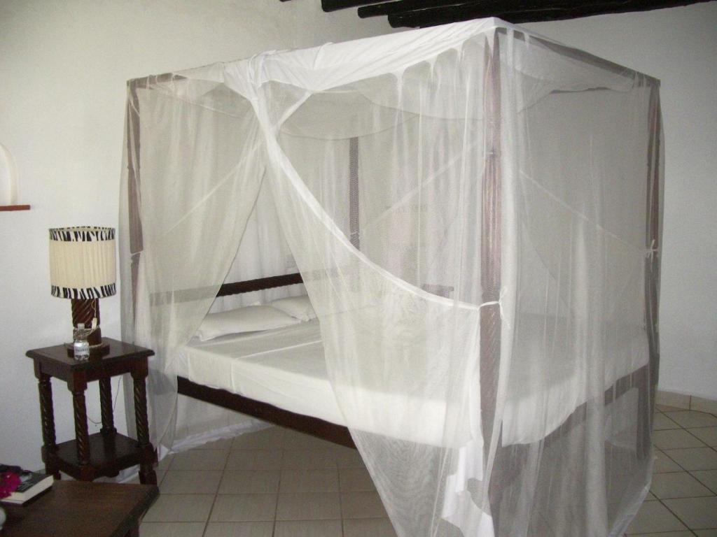 a bedroom with a canopy bed with white curtains at Empiris Lodge in Sekenani