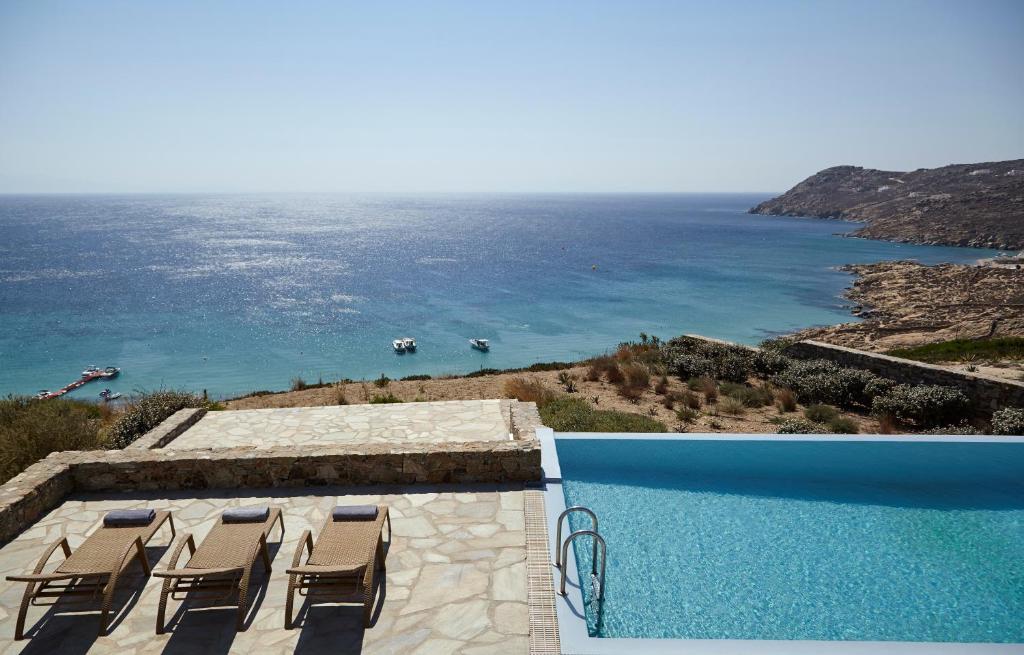 una piscina con sillas y vistas al océano en Elia White Residence, en Playa de Elia