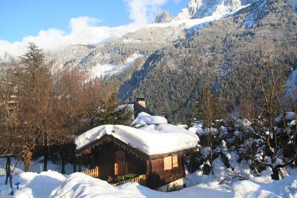 eine schneebedeckte Hütte mit einem Berg im Hintergrund in der Unterkunft Chalet Alpine Rose in Chamonix-Mont-Blanc