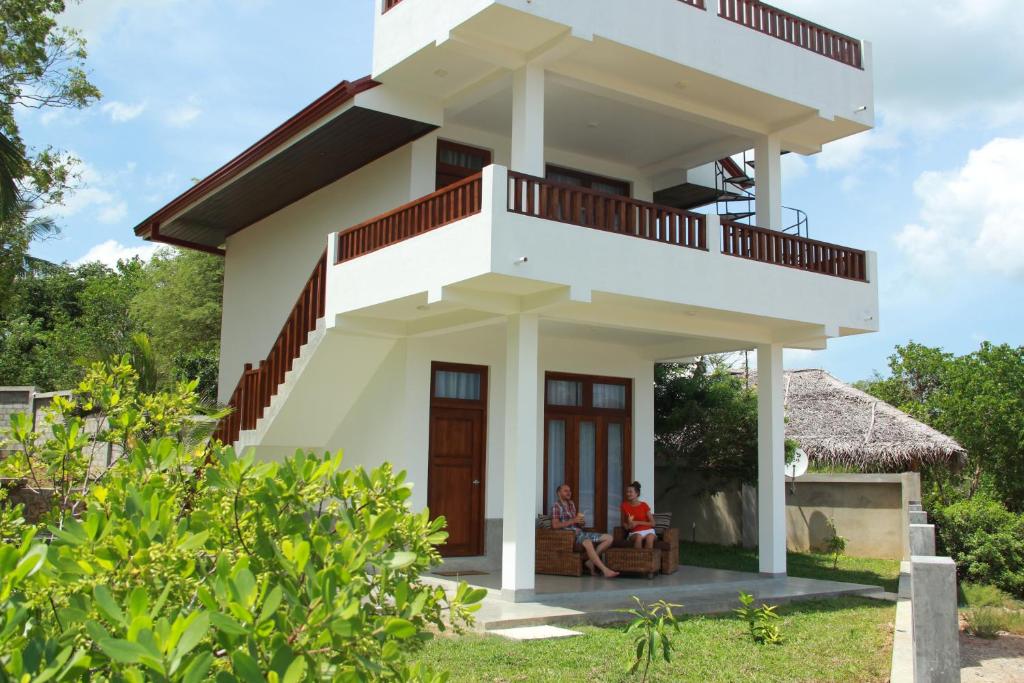 dos personas sentadas frente a una casa en Hideaway Lodge, en Tangalle