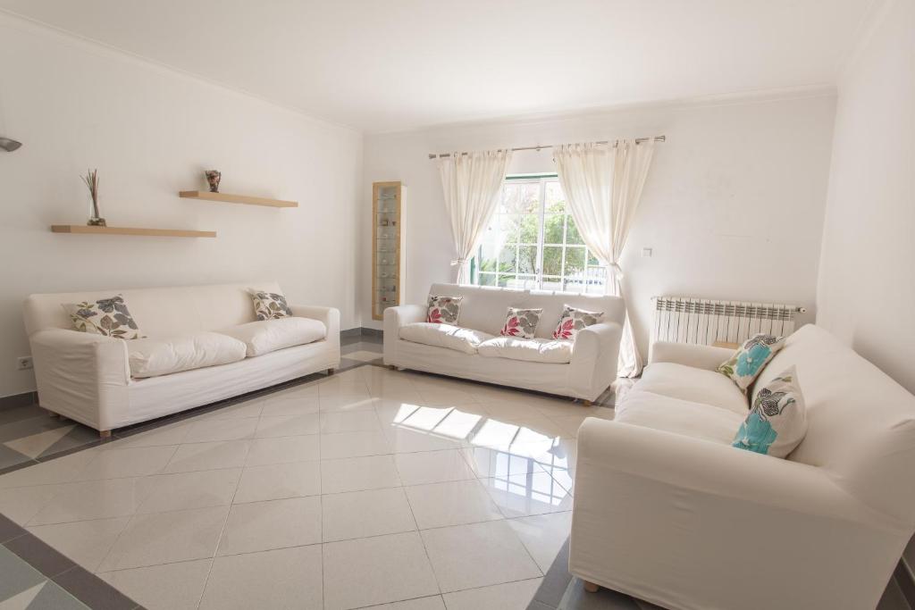uma sala de estar com dois sofás brancos e uma janela em Casa Bordalo - Family, Beach, Culture and Surf nas Caldas da Rainha