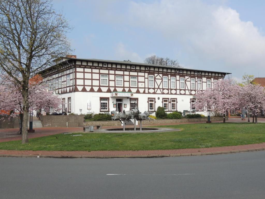 a large white building with flowering trees in front of it at Deutsches Haus Munster in Munster im Heidekreis