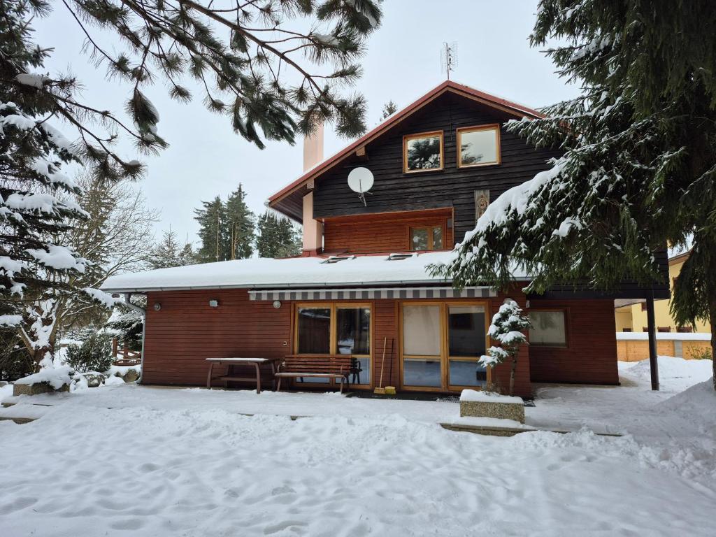 a log house in the snow with a porch at Chata Levagri in Liptovský Mikuláš
