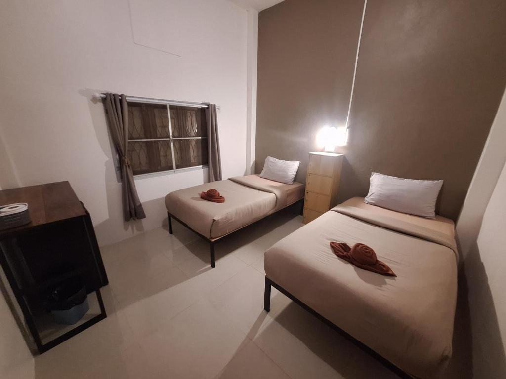 a small room with two beds and a tv at Sabai Sabai Bed in Pai