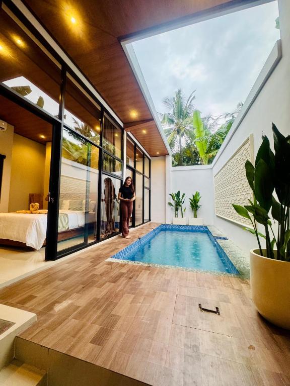 a person standing next to a swimming pool in a house at Griya Becik Lovina - Private Pool Villa near Lovina Dolphin Spot in Lovina