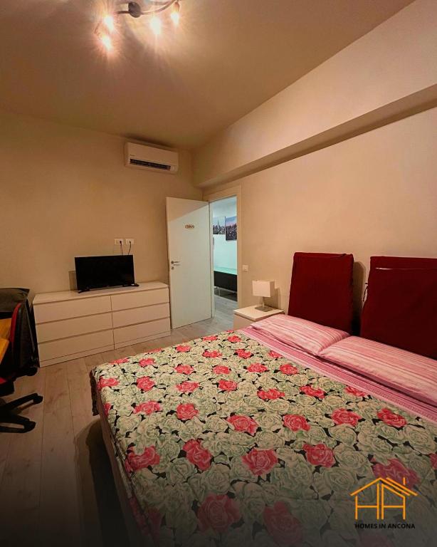 a bedroom with a large bed with a floral blanket at CarloAlberto23- Rooms by Homes in Ancona in Ancona