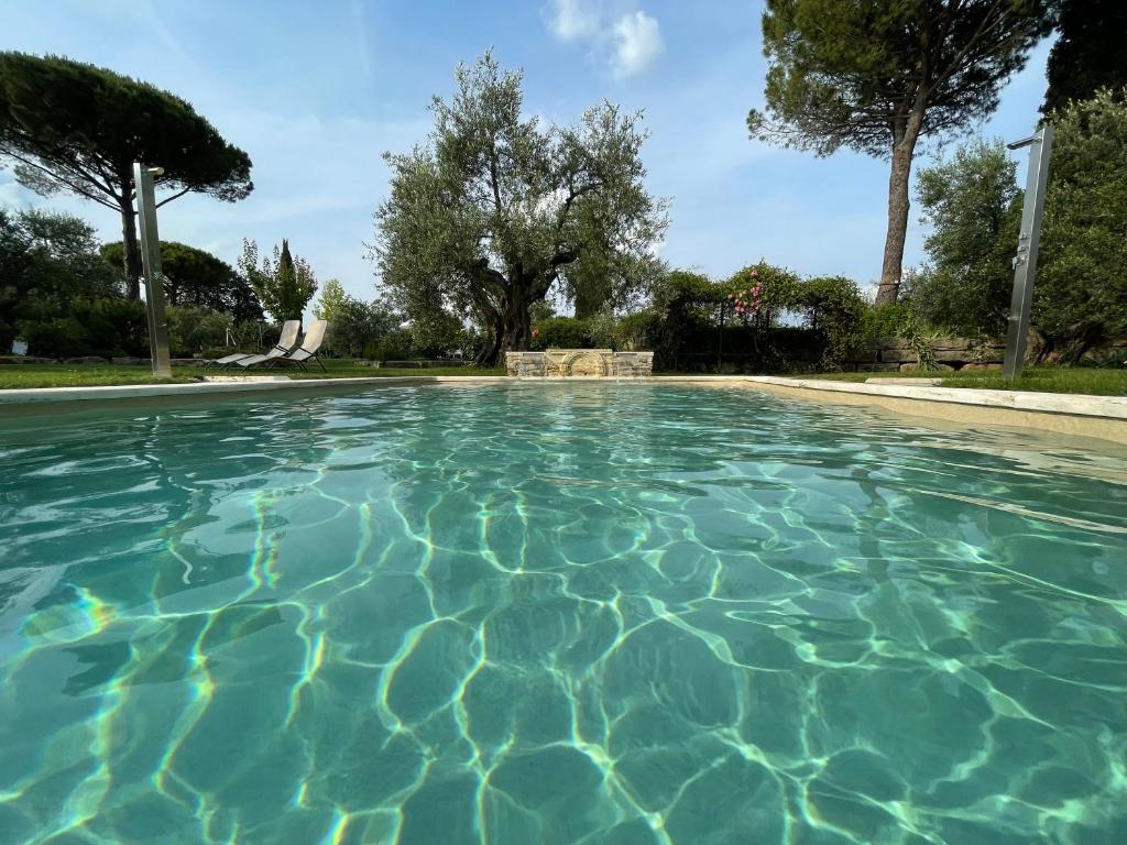 a pool of blue water with trees in the background at Le Balze Camere in Villa in Perugia