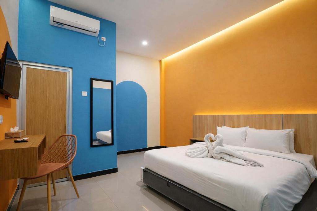 a hotel room with a bed and a table and chair at Tripletree Kenaro Hotel in Blimbing