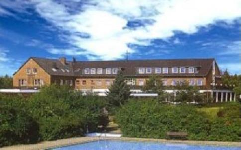 a large building with a swimming pool in front of it at Heidehotel Herrenbrücke in Faßberg