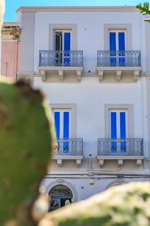 a white building with blue windows and balconies at Liberty Palace in Milazzo