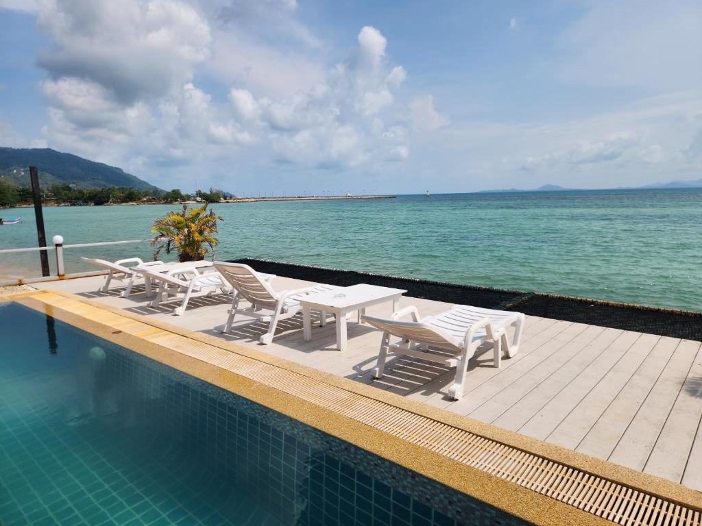 a swimming pool with tables and chairs next to the water at Ko Phangan Beach Cottages in Ban Tai