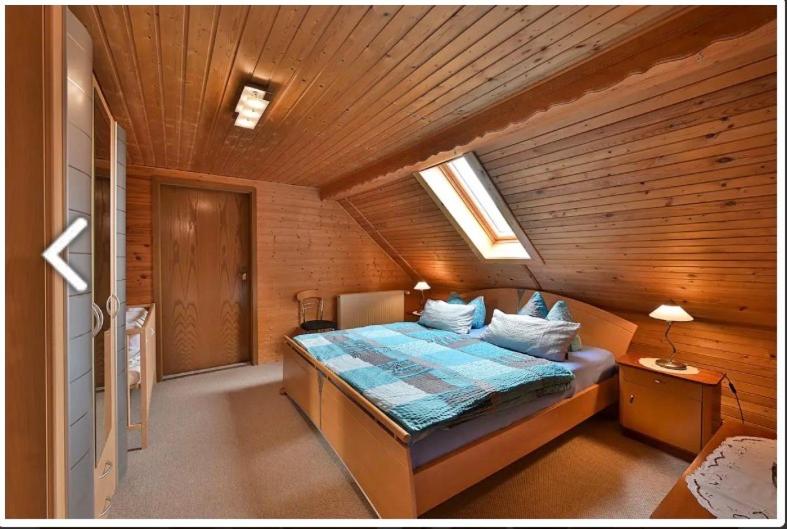 a bedroom with a bed in a wooden room at Gerstels Ferienhof in Hörselberg-Hainich