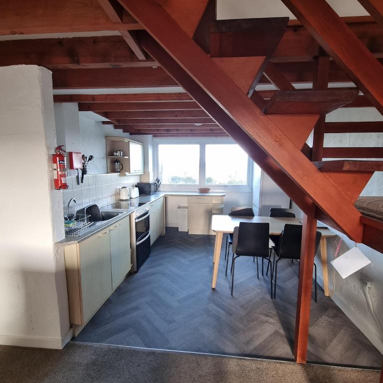 a kitchen with wooden ceilings and a table and chairs at Penrhyn Cottage Tyn Don in Llanengan