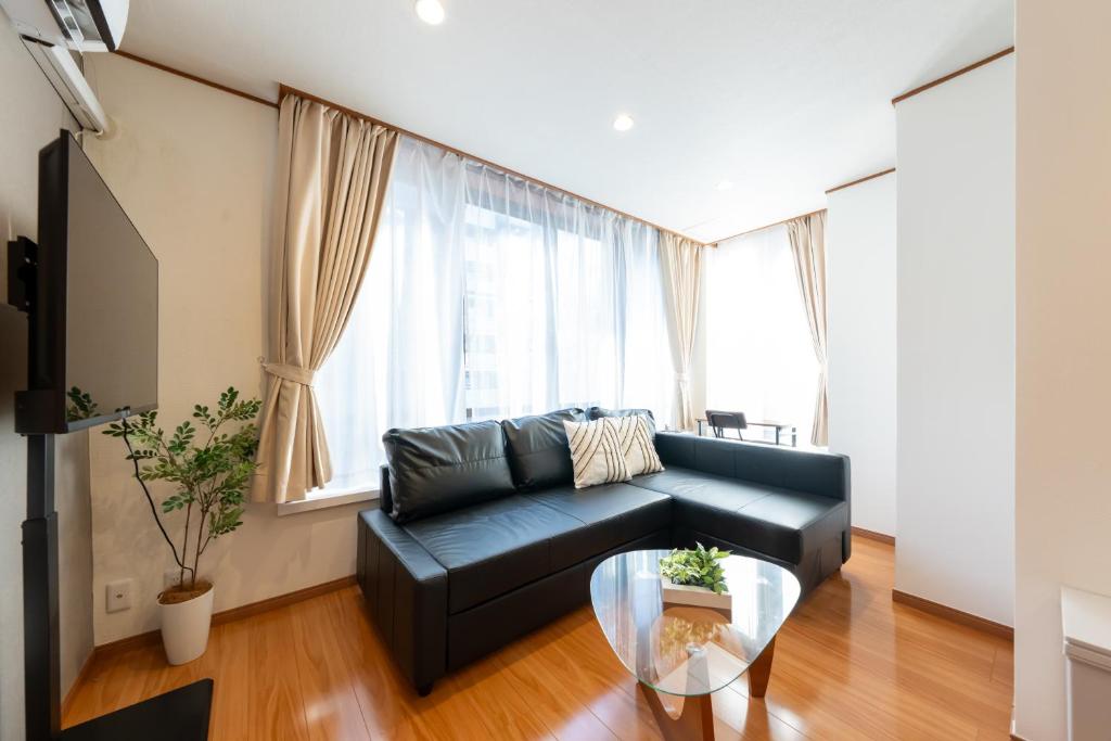 a living room with a black couch and a glass table at NTK House Yokohama in Yokohama