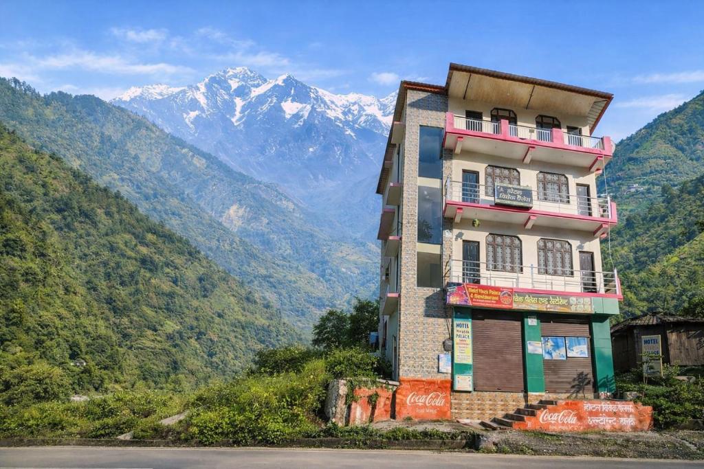 a building on a hill with mountains in the background at Hotel Vivek Palace in Uttarkāshi