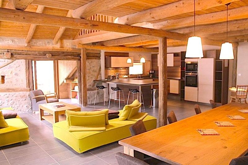 a kitchen and living room with yellow chairs and a table at 10214 Chalet d'exception nature sport et bien être sauna,jacuzzi hammam frigidarium in Cervières