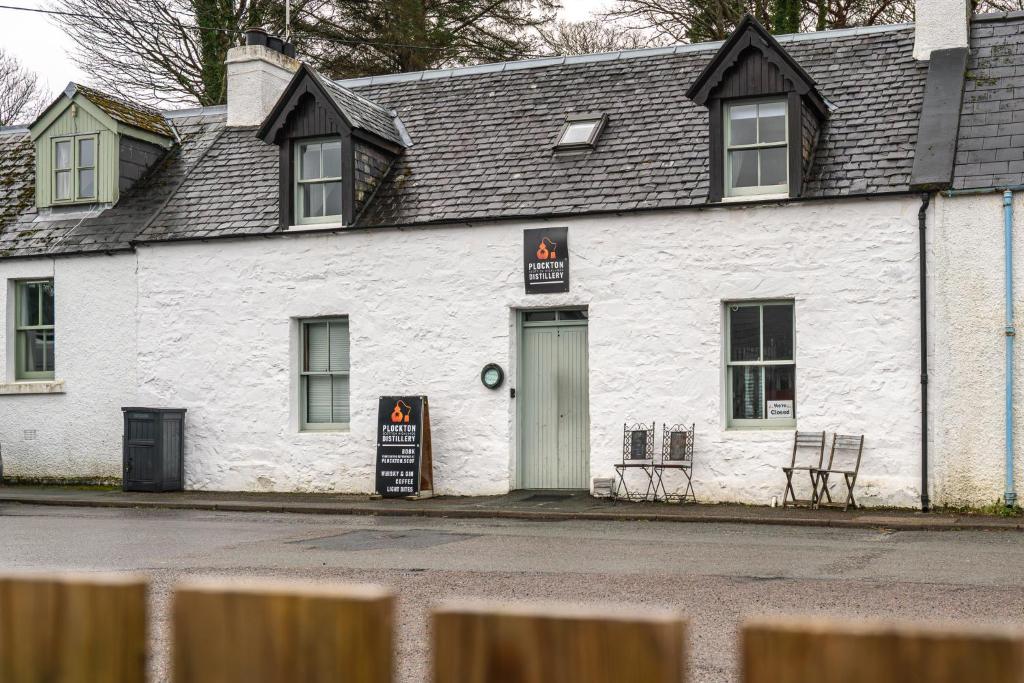 a white building with a sign in front of it at Plockton Distillery Flat in Plockton